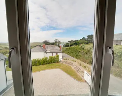 a window with a view of a house and a driveway at Worthy House in Polzeath