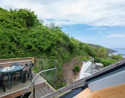 a balcony with a table and a view of the ocean at April Cottage in Port Isaac
