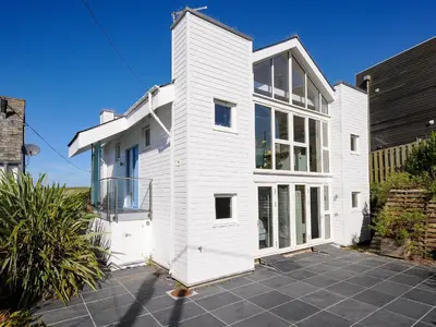 a white house with a lot of windows at Drishti in Polzeath