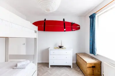 a bedroom with a bed and a red chandelier at Bella Vista in Polzeath