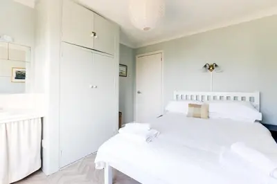 a white bedroom with two beds and a sink at Bella Vista in Polzeath