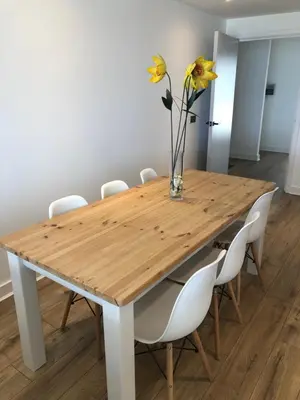 a wooden table with white chairs and a vase with flowers at The Towan Lookout in Newquay