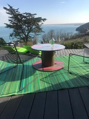 a table and chairs on a deck with a view of the ocean at Chy conary in Carbis Bay