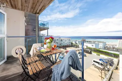 a balcony with a table and chairs and the ocean at 45 Ocean 1, Newquay in Crantock