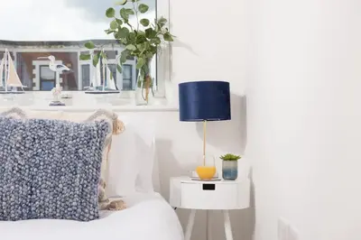 a bedroom with a bed with a blue lamp on a side table at 45 Ocean 1, Newquay in Crantock