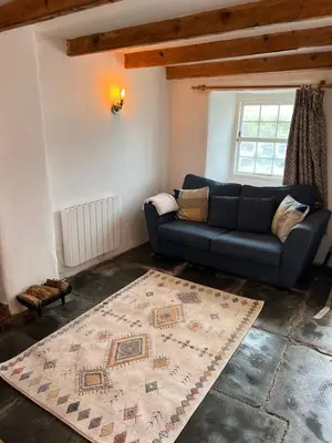 a living room with a blue couch and a rug at The Cottage St Kew in Port Isaac