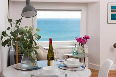 a dining room table with a bottle of wine and glasses at Stunning Sea Views, Wi-Fi, Pet Friendly in Marazion