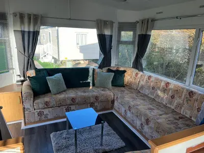 a living room with a couch and windows at Cornish coastal retreats- 74 newquay view in Porth