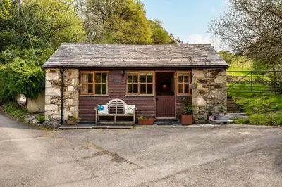 a small house with a bench in front of it at Romantic, secluded cottage in Cardinham Woods, Cornwall in Cardinham