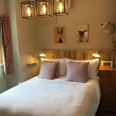 a bedroom with a bed with white sheets and pillows at Romantic, secluded cottage in Cardinham Woods, Cornwall in Cardinham