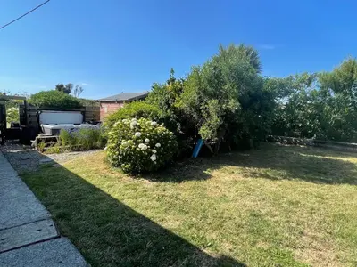 a garden with a bush in the grass at Baywatch Mawgan Porth Spacious Home sleeps 9, Games room, Parking & Garden in Mawgan Porth