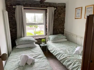 two twin beds in a room with a window at Buttercup Cottage, located in the gateway to Eden! in Saint Blazey