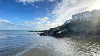 a building on a cliff next to the ocean at Looe with a View - Entire apartment with FREE allocated parking in Looe