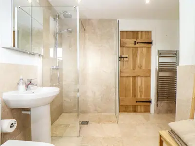 a bathroom with a shower and a sink and a shower stall at Polurrian House in Helston