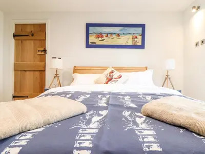 a bedroom with a bed with a blue blanket at Polurrian House in Helston