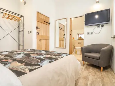 a bedroom with a bed and a chair and a tv at Polurrian House in Helston