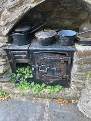 an old stone oven with pots and pans on it at The Granary at Bissick Old Mill in Truro