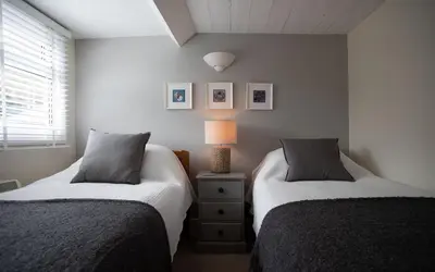a bedroom with two beds and a lamp on a night stand at Brakestone Cottage in the heart of Port Isaac in Port Isaac