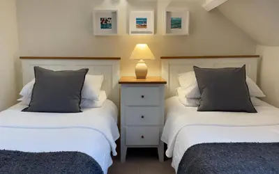 two beds sitting next to each other in a bedroom at Brakestone Cottage in the heart of Port Isaac in Port Isaac