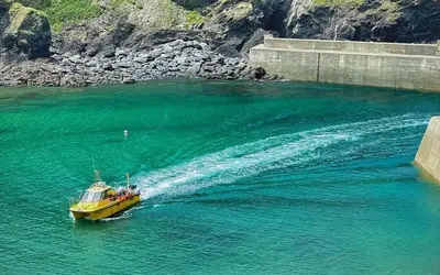 a yellow boat in the water near a bridge at Brakestone Cottage in the heart of Port Isaac in Port Isaac