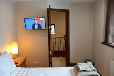 a bedroom with a bed with a television on the wall at White Hart Cottage, Menheniot, Nr Looe in Menheniot