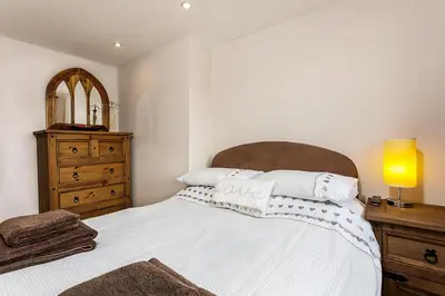 a bedroom with a bed and a dresser with a mirror at White Hart Cottage, Menheniot, Nr Looe in Menheniot