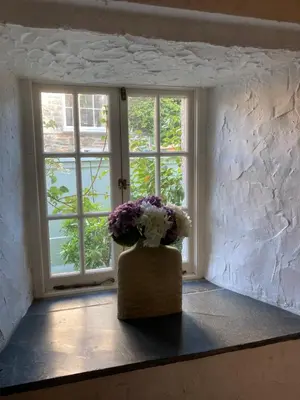 a vase of flowers sitting in front of a window at Bissick Old Mill Suite in Truro