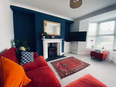 a living room with a red couch and a fireplace at Beautiful 2 bed end terrace Victorian town house in Redruth
