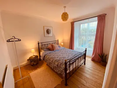 a bedroom with a bed and a large window at Beautiful 2 bed end terrace Victorian town house in Redruth