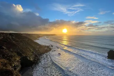 a sunset over a beach with the sun setting at Kerensa in Portreath