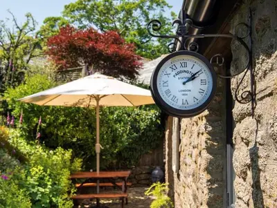 a clock on the side of a building with an umbrella at The Lambing Shed, Cornwall in Altarnun