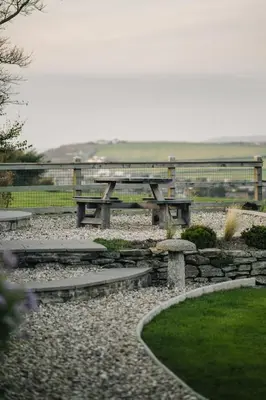 a picnic table and benches in a park at Sea View at Widemouth Bay - 3 bedroom cottage in Poundstock