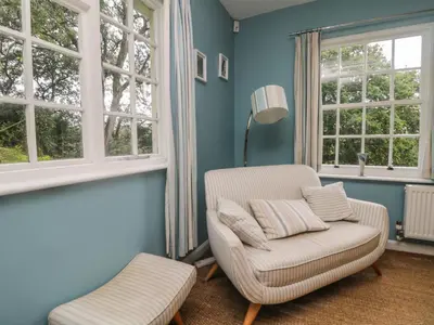 a blue living room with a chair and window at Gweek House in Helston
