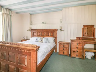 a bedroom with a wooden bed and a wooden dresser at Dovecote in Saint Goran