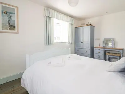 a white bedroom with a white bed and a window at Owls Roost in Saint Goran