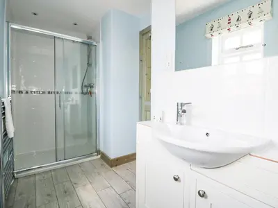 a white bathroom with a shower and a sink at Squirrels Dray in Saint Goran