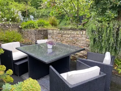 a patio with a table and chairs in a garden at Fuchsia Cottage in Flushing