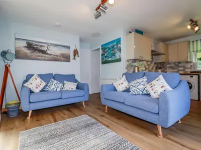 a living room with two blue couches and a kitchen at Woodside in Liskeard