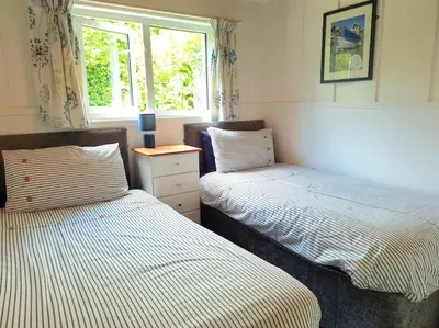 a bedroom with two beds and a window at Kallowen Cottage at Crackington Haven, near Bude and Boscastle, Cornwall in Bude