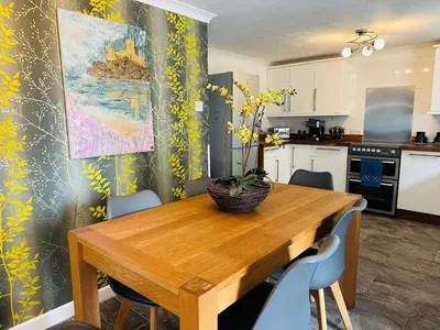 a kitchen with a wooden table and blue chairs at Bay View Cottage in St Austell