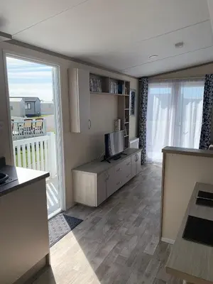 a living room with a television and a balcony at Beautiful Cornish Getaway, Static Caravan - Newperran Holiday Resort in Cubert