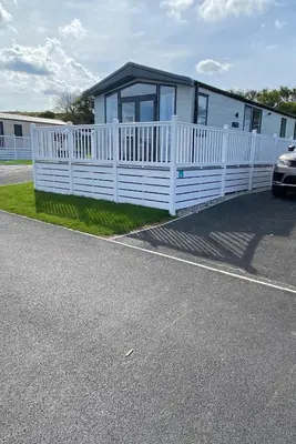 a house with a white fence next to a road at Riverwood Lodge in Porth