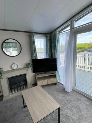 a living room with a flat screen tv and a fireplace at Riverwood Lodge in Porth