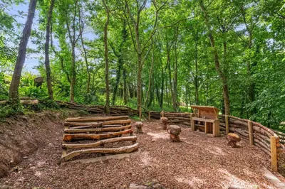 a group of logs and a fence in the woods at House 1 in Looe