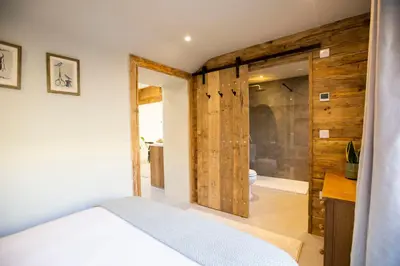a bedroom with a bed and a bathroom at Mowhay Barn in Bodmin