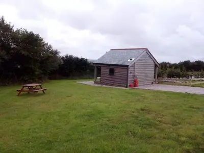 a picnic table in a field next to a shed at Hawk's Nest in Wadebridge