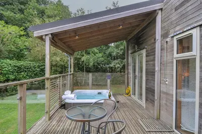 a deck with a hot tub and a table and chairs at 3 Southern Place in Liskeard