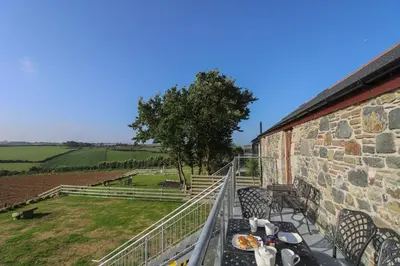 a balcony with tables and chairs on a building at Pol Glas Hall in Helston