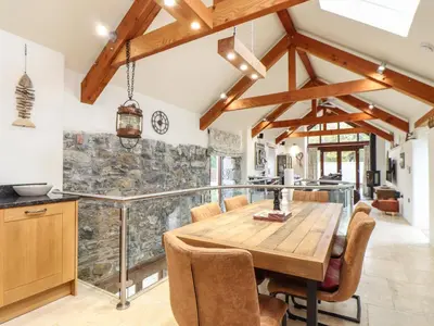 a kitchen and dining room with a wooden table and chairs at Pol Glas Hall in Helston