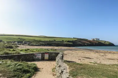 a sandy beach with a building on it next to the water at Pol Glas Hall in Helston